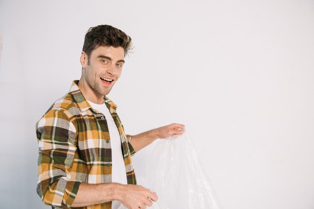 улыбающийся молодой человек с целлофаном во время подготовки к настенной живописи
 - Фото, изображение