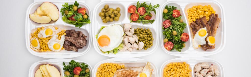 tiro panorâmico de pacotes ecológicos com maçãs, legumes, carne, ovos fritos e saladas em fundo branco
  - Foto, Imagem