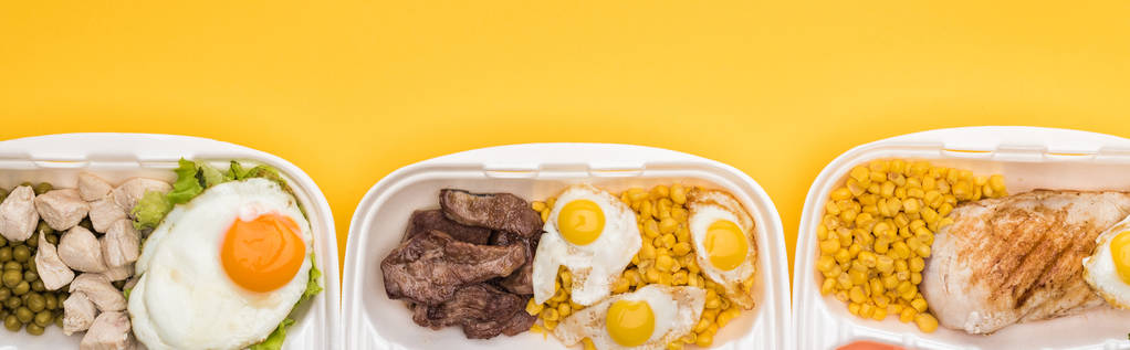 panoramiczne ujęcie opakowań ekologicznych z warzywami, mięsem, jajami smażonymi izolowanymi na żółto     - Zdjęcie, obraz