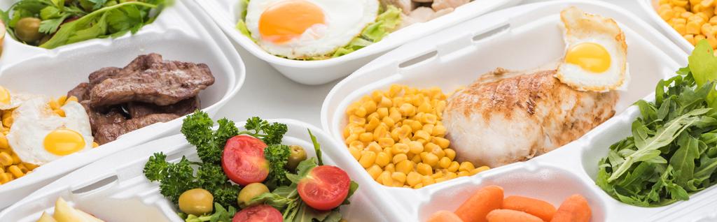 panoramisch shot van eco-pakketten met groenten, vlees, gebakken eieren en salades op witte achtergrond  - Foto, afbeelding
