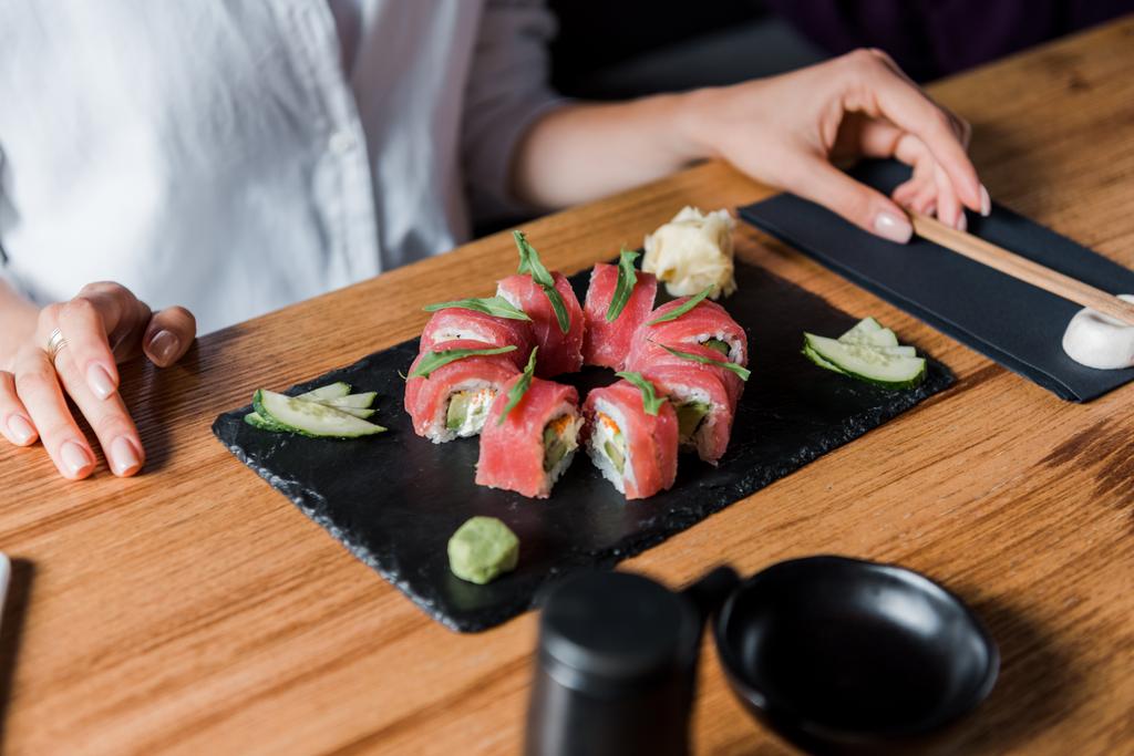 vista cortada de jovem mulher tocando pauzinhos perto de sushi saboroso
  - Foto, Imagem