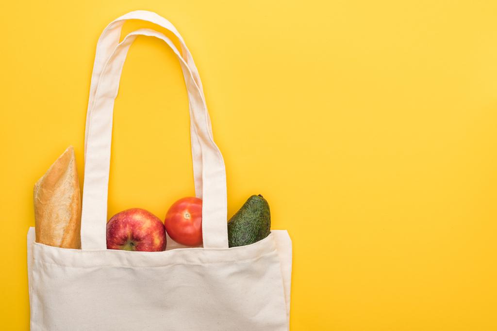vista superior de maçãs maduras, baguete e abacate em sacos ecológicos isolados em amarelo
 - Foto, Imagem