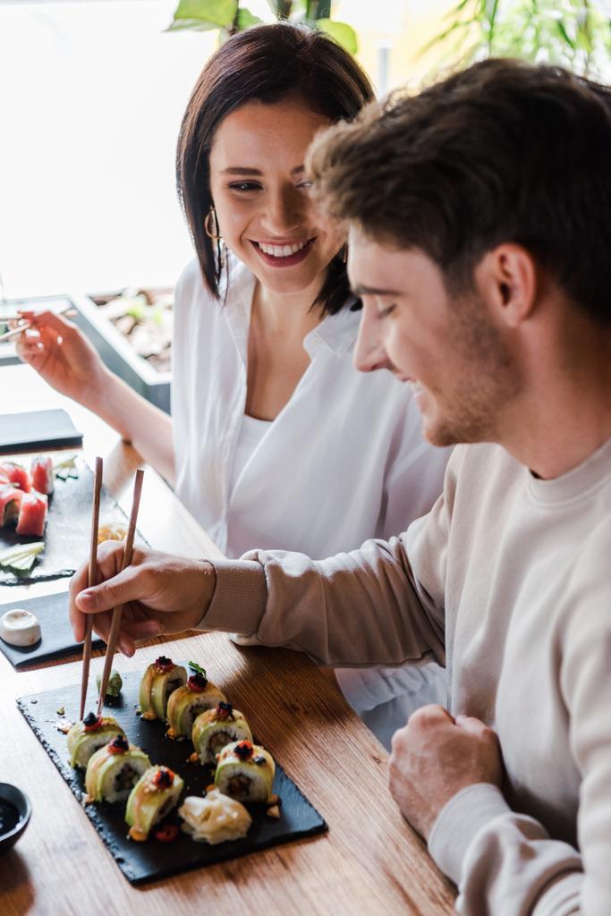 selektivní zaměření mladé ženy při pohledu na muže v sushi baru - Fotografie, Obrázek