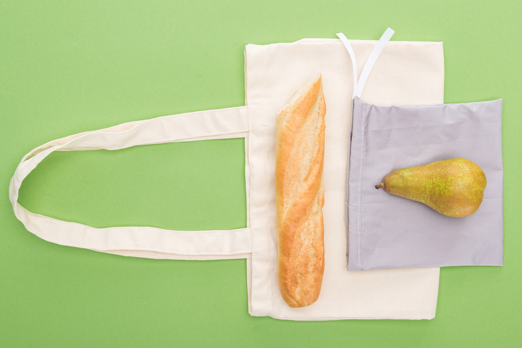 вид зверху на грушу і багет на екологічно чистих сумках ізольовані на зеленому
 - Фото, зображення