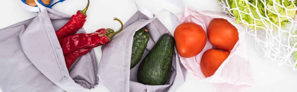 top view of fresh avocados, tomatoes and chili peppers in eco friendly bags isolated on white, panoramic shot - Photo, Image