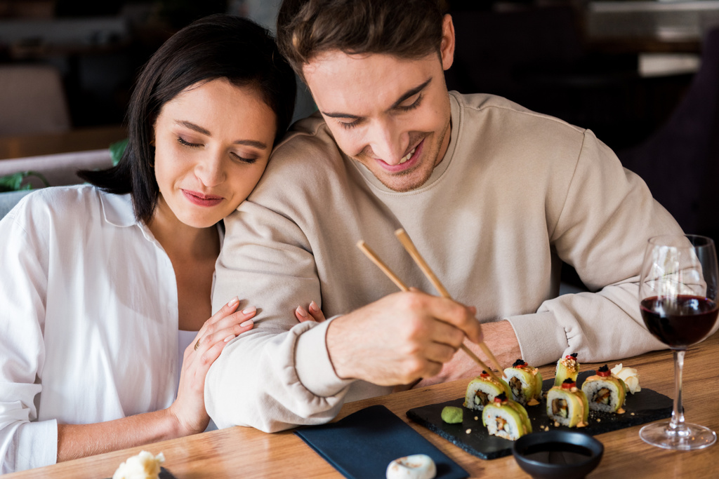 hombre feliz sosteniendo palillos cerca de sushi cerca de mujer atractiva
  - Foto, imagen