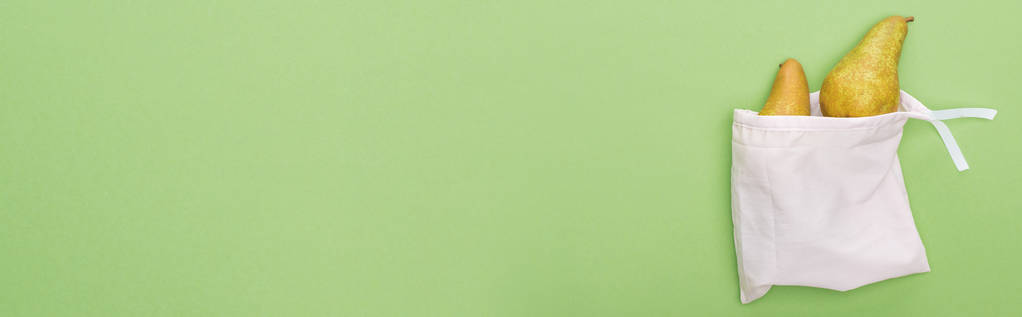 Κορυφαία όψη των αχλαδιών σε φιλική προς το οικολογικό λευκό σάκο απομονωμένη σε πράσινο, πανοραμική βολή - Φωτογραφία, εικόνα