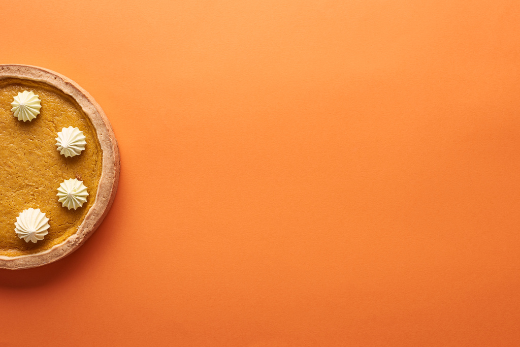 vista superior de delicioso pastel de calabaza con crema batida en la superficie naranja con espacio de copia
 - Foto, Imagen