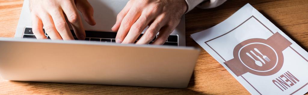 panoramic shot of woman typing on laptop near menu on table  - Photo, Image
