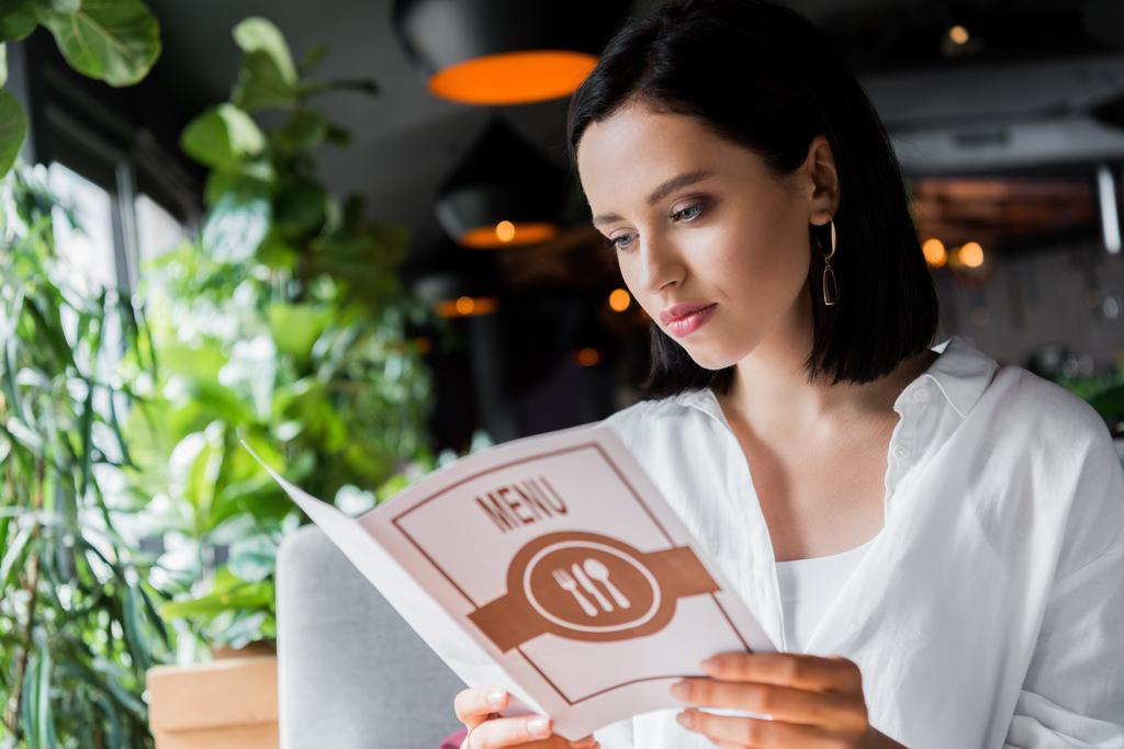привлекательная молодая женщина смотрит меню в ресторане
  - Фото, изображение