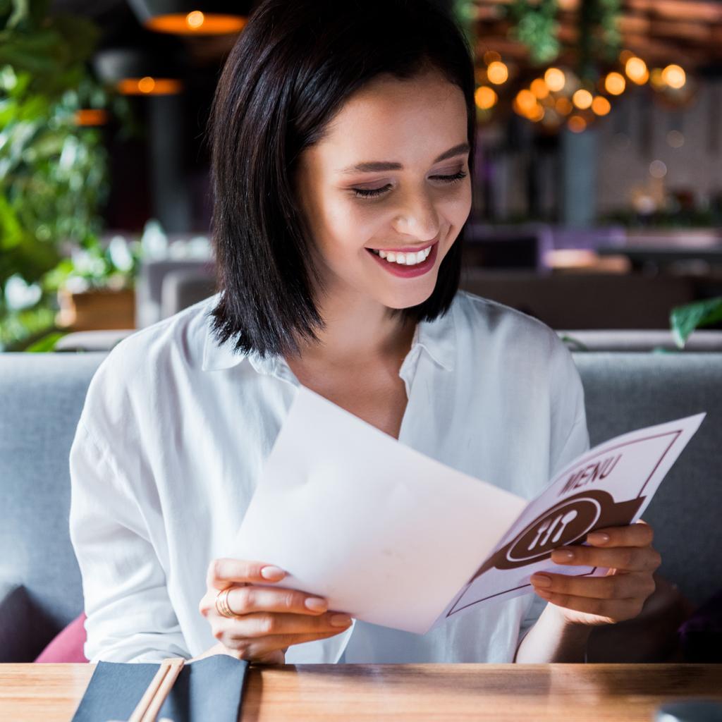 foco seletivo da mulher alegre sentada no bar de sushi e olhando para o menu
  - Foto, Imagem