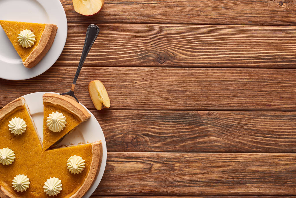 deliciosa torta de abóbora com chantilly perto da maçã de corte na mesa de madeira marrom
 - Foto, Imagem