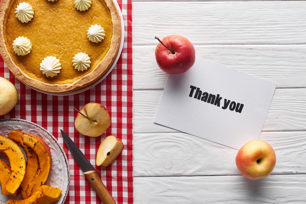 pohled na dýňový koláč, zralý jablka a přání poděkování na dřevěném bílém stole - Fotografie, Obrázek