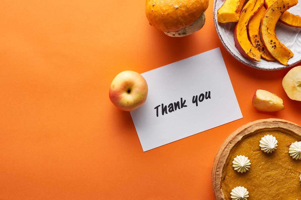 Ansicht von Kürbiskuchen, reifen Äpfeln und Dankeskarte auf orangefarbenem Hintergrund - Foto, Bild