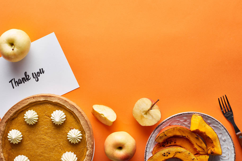 vista superior de torta de abóbora, maçãs maduras e cartão de agradecimento no fundo laranja
 - Foto, Imagem