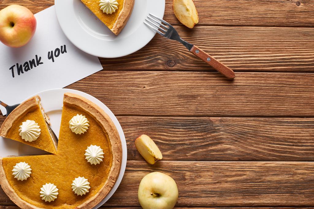 vue du dessus de tarte à la citrouille, pommes mûres et carte de remerciement sur table brune en bois
 - Photo, image