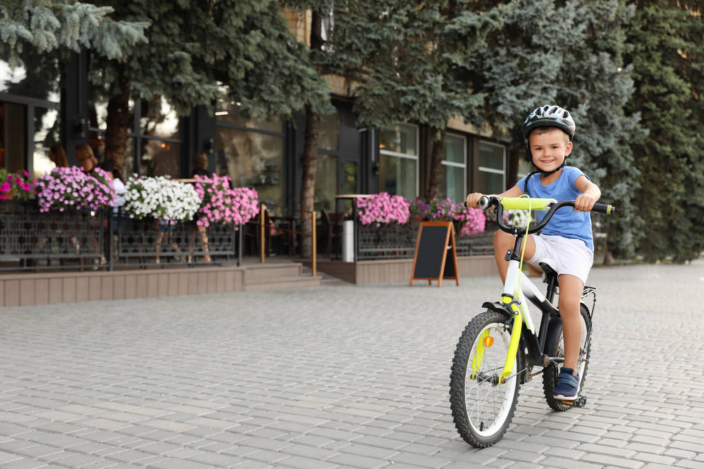 Onnellinen pieni poika kypärä ratsastus polkupyörällä kadulla
 - Valokuva, kuva