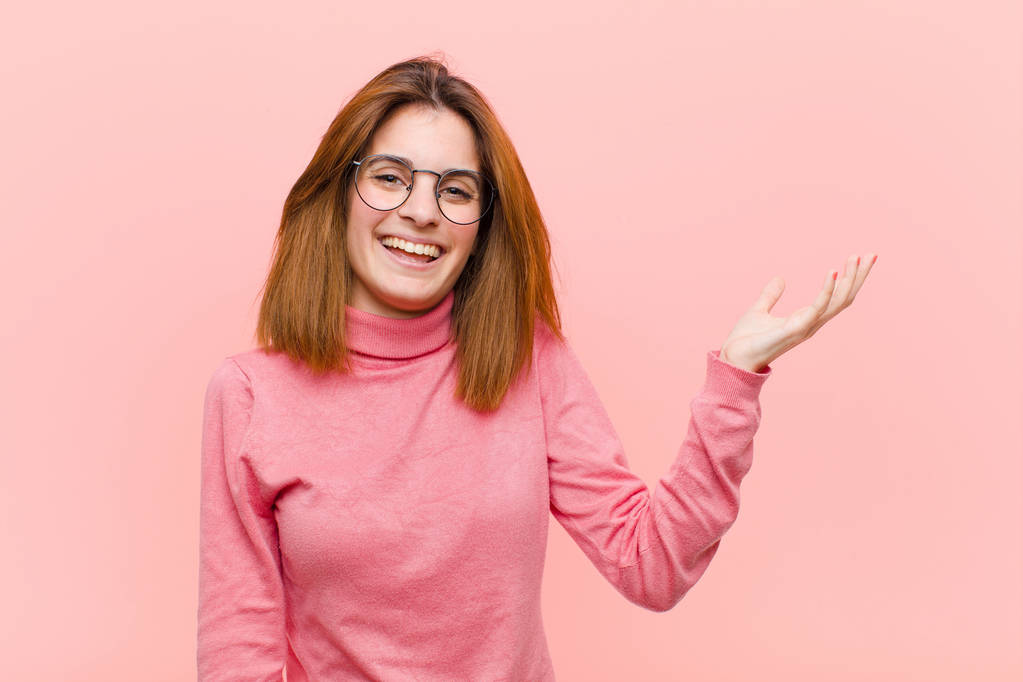 young pretty woman feeling happy, surprised and cheerful, smiling with positive attitude, realizing a solution or idea against pink background - 写真・画像