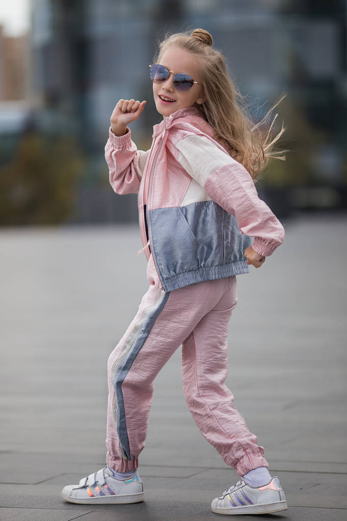 Танцующая брейк девочка. Спортивная маленькая девочка в моде спортивная одежда делает фитнес-упражнения на улице, открытый спорт, городской стиль
 - Фото, изображение