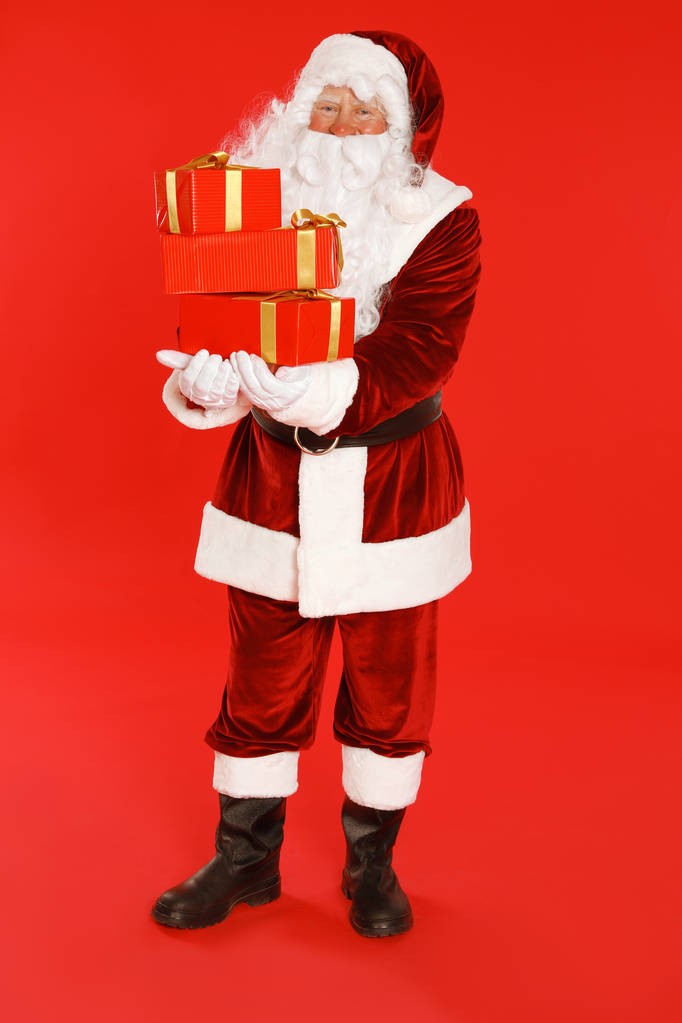 Справжній Дід Мороз з подарункові ящики на червоному фоні - Фото, зображення