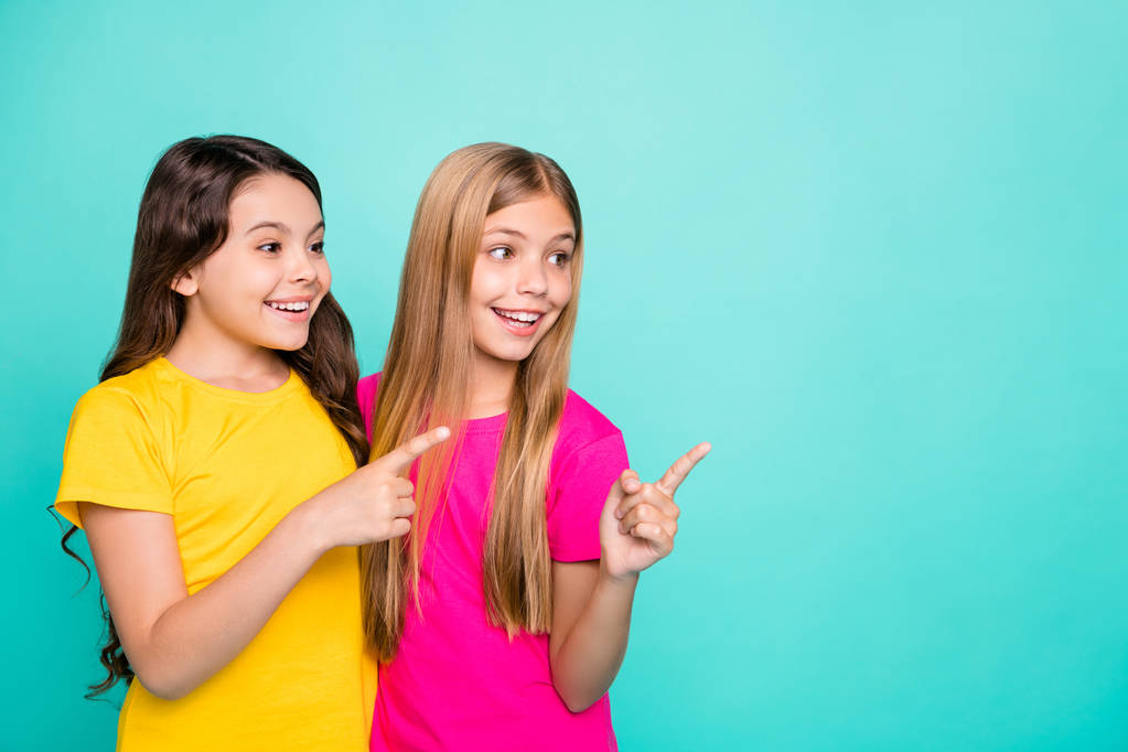 Photo of two casual girls having noticed something interesting while isolated with teal background - Photo, Image