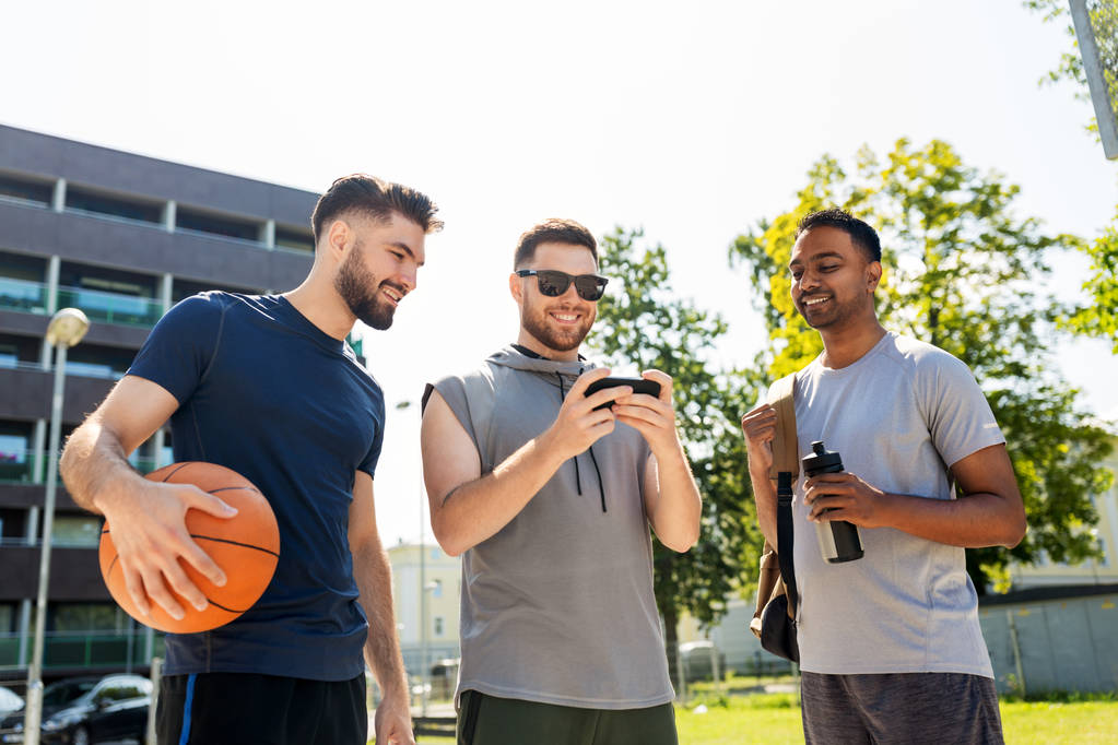 férfiak okostelefon a kosárlabda játszótéren - Fotó, kép
