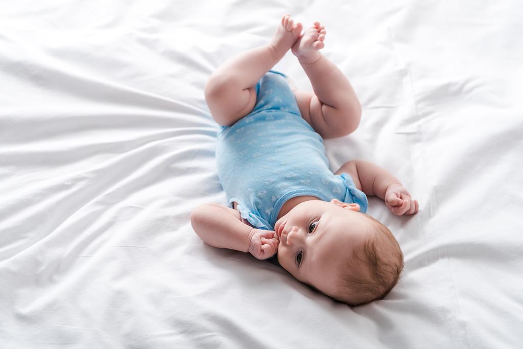 adorable bébé en bébé barboteuse couché sur le lit à la maison
  - Photo, image