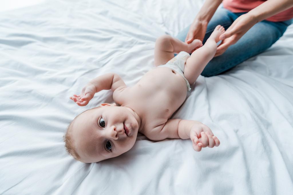 levágott kilátás anya megható lábak aranyos csecsemő baba otthon  - Fotó, kép