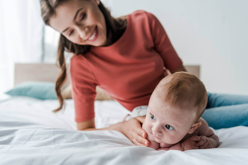 szelektív fókusz aranyos csecsemő baba közelében gyönyörű anya a hálószobában  - Fotó, kép