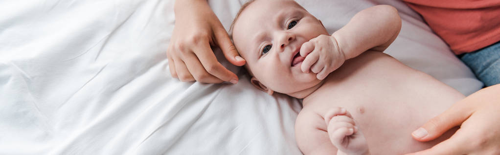 colpo panoramico di madre premurosa toccando bambino carino sul letto
  - Foto, immagini