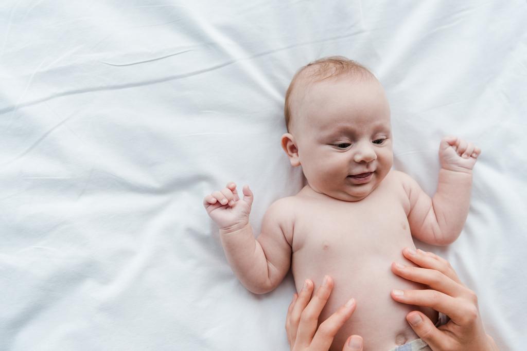 vue de dessus de la mère touchant fille bébé souriante sur le lit
  - Photo, image