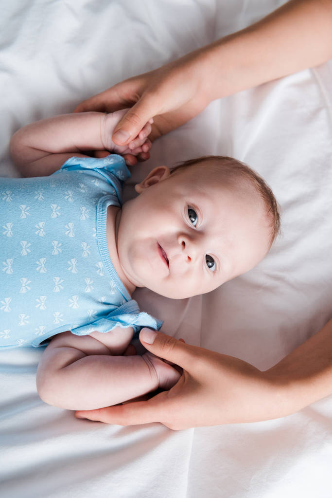 Mavi bebek tulumu giymiş güzel bir bebeğin el ele tutuşan annesinin görüntüsü.  - Fotoğraf, Görsel