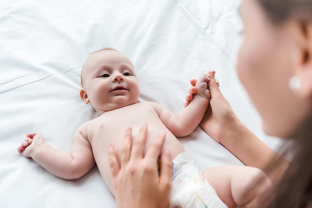 valikoiva painopiste huolehtiva äiti koskettaa söpö pikkulapsi tytär sängyssä
  - Valokuva, kuva