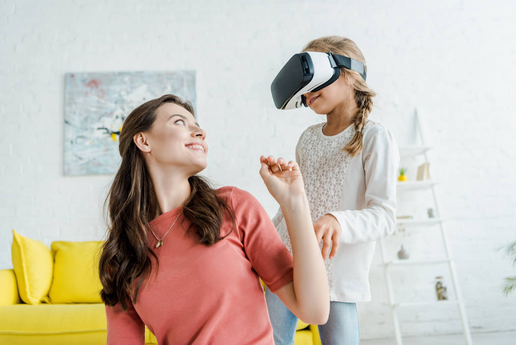 счастливая няня смотрит на веселого ребенка в наушниках виртуальной реальности
  - Фото, изображение