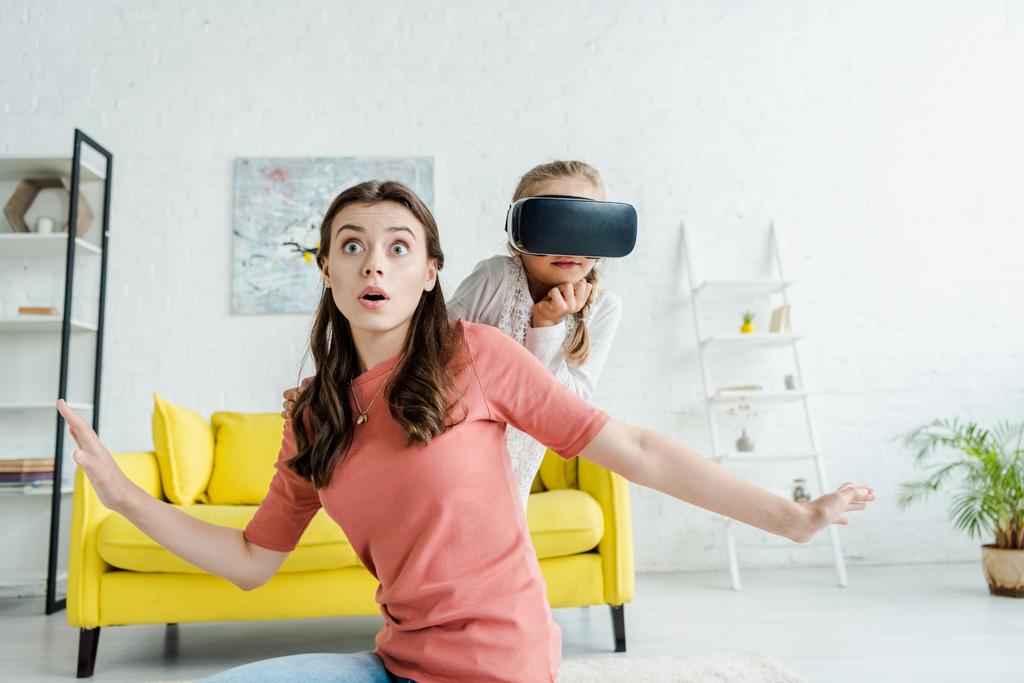 yllättynyt lapsenvahti ojennetut kädet lähellä lapsi virtuaalitodellisuus kuulokkeet
  - Valokuva, kuva