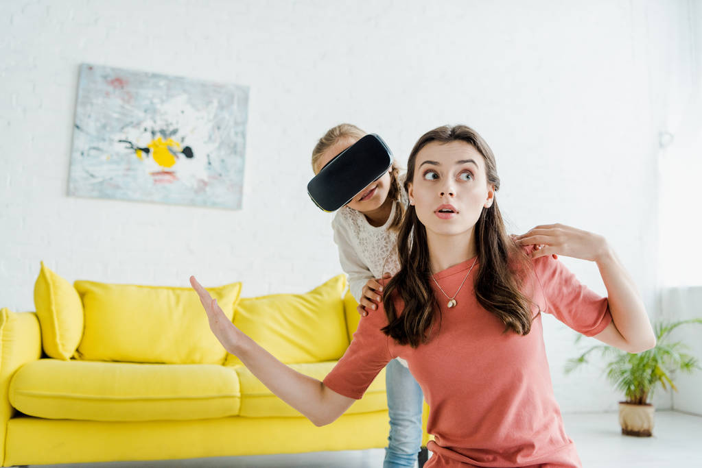 babysitter surpris avec les mains tendues près de l'enfant dans le casque de réalité virtuelle
  - Photo, image