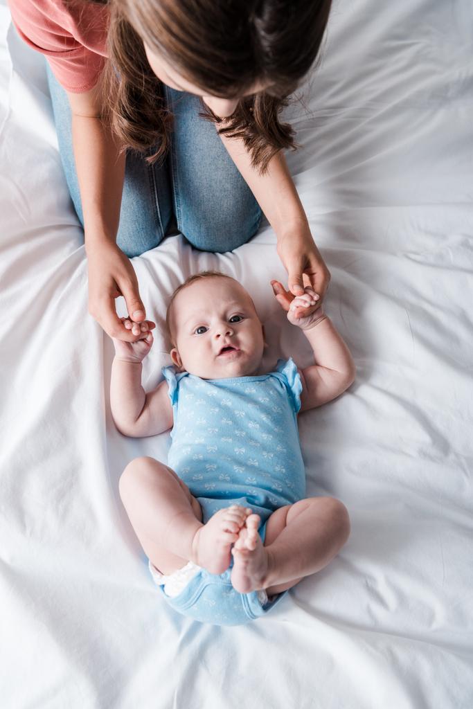 vue du dessus de la mère en jean denim assis près d'adorable bébé en body bleu
  - Photo, image