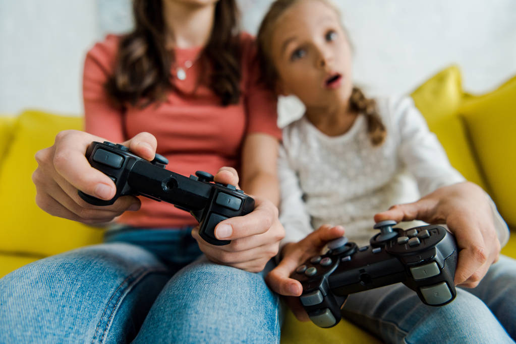 KYIV, UCRANIA - 4 de septiembre de 2019: enfoque selectivo de la niñera y el niño sorprendido jugando videojuegos en la sala de estar
  - Foto, Imagen