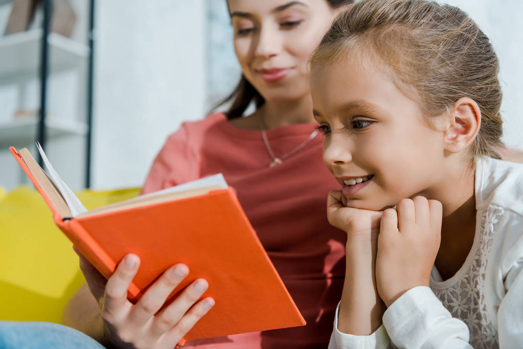 избирательный фокус счастливого ребенка глядя на книгу рядом счастливая няня
  - Фото, изображение