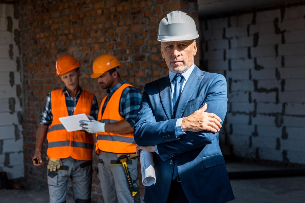 selective focus of businessman standing with crossed arms near constructors - Photo, Image