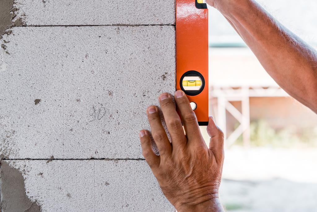 обрезанный вид зрелого человека, измеряющего бетонную стену
  - Фото, изображение