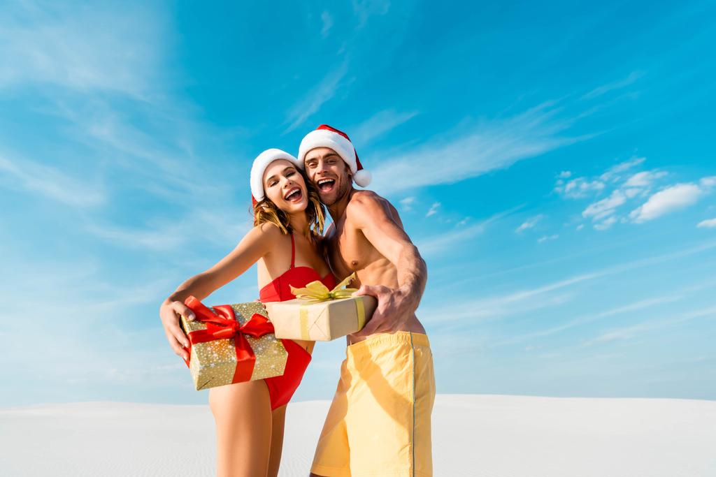 sexy and smiling girlfriend and boyfriend holding gifts on beach in Maldives  - Photo, Image