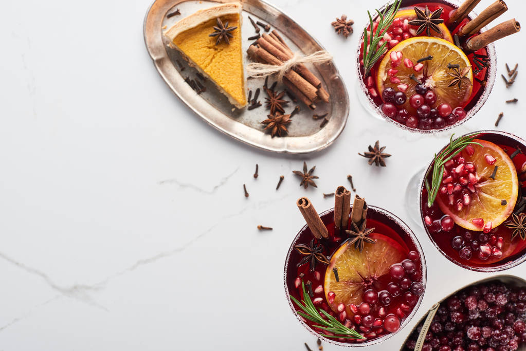 Draufsicht auf Weihnachtscocktails mit Orange, Granatapfel, Zimt, gefrorenen Preiselbeeren und Kuchen - Foto, Bild