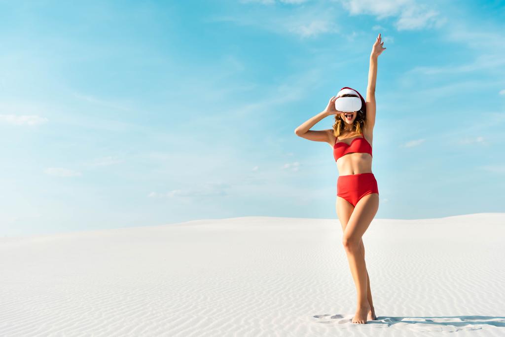 Сексуальна жінка в Санта капелюсі і купальник з головою віртуальної реальності на пляжі в Мальдівах.  - Фото, зображення