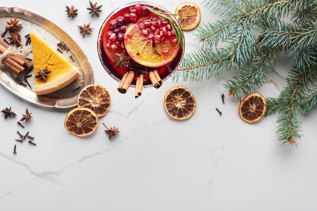 vrchní pohled na vánoční koktejl s pomerančem, granátovým jablkem, skořicí a koláčem na tácu  - Fotografie, Obrázek