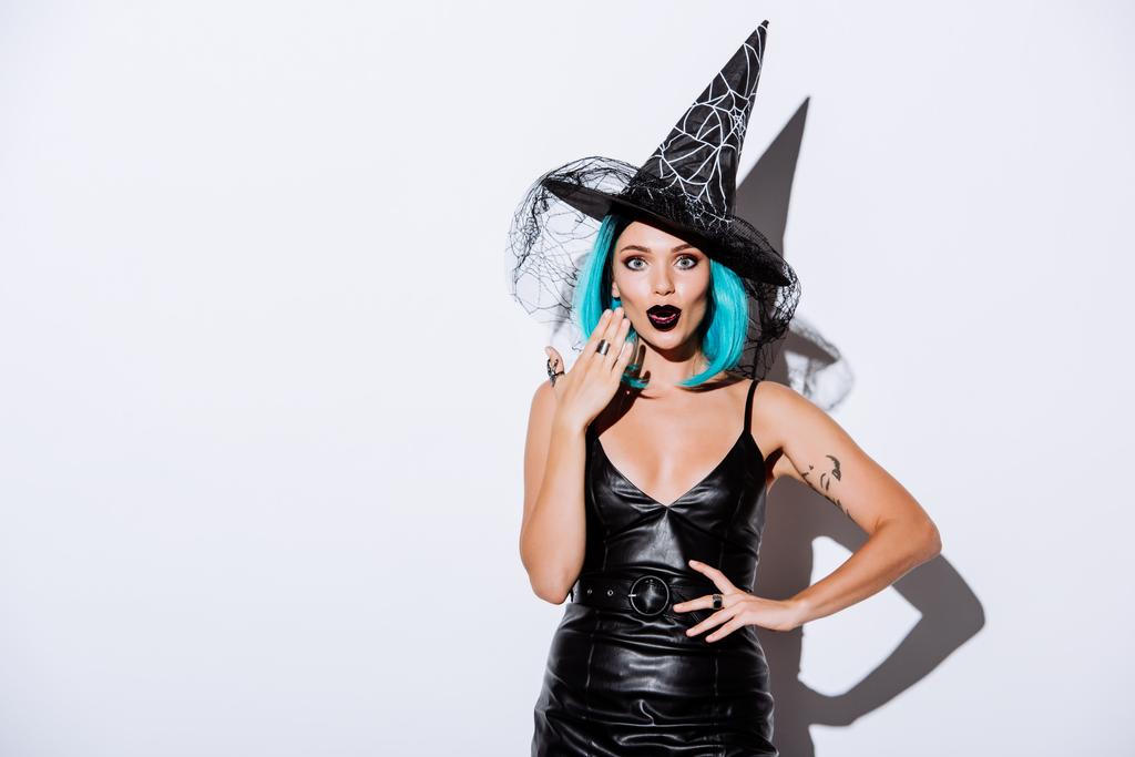 шокированная девушка в костюме черной ведьмы Хэллоуин с голубыми волосами на белом фоне
 - Фото, изображение