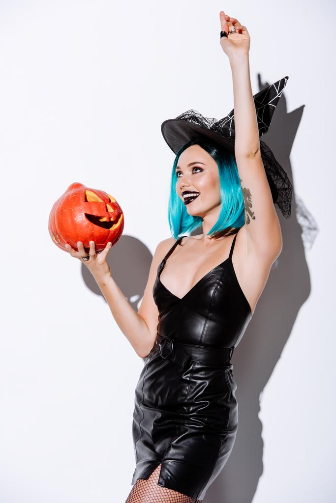chica sexy en traje de Halloween bruja negro con pelo azul celebración espeluznante calabaza tallada sobre fondo blanco
 - Foto, imagen