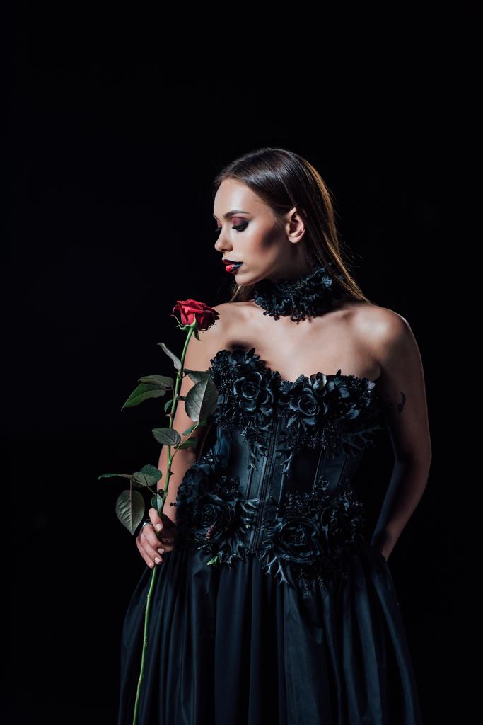 przerażający wampir dziewczyna w czarny gotycki sukienka gospodarstwa czerwona róża odizolowany na czarny - Zdjęcie, obraz