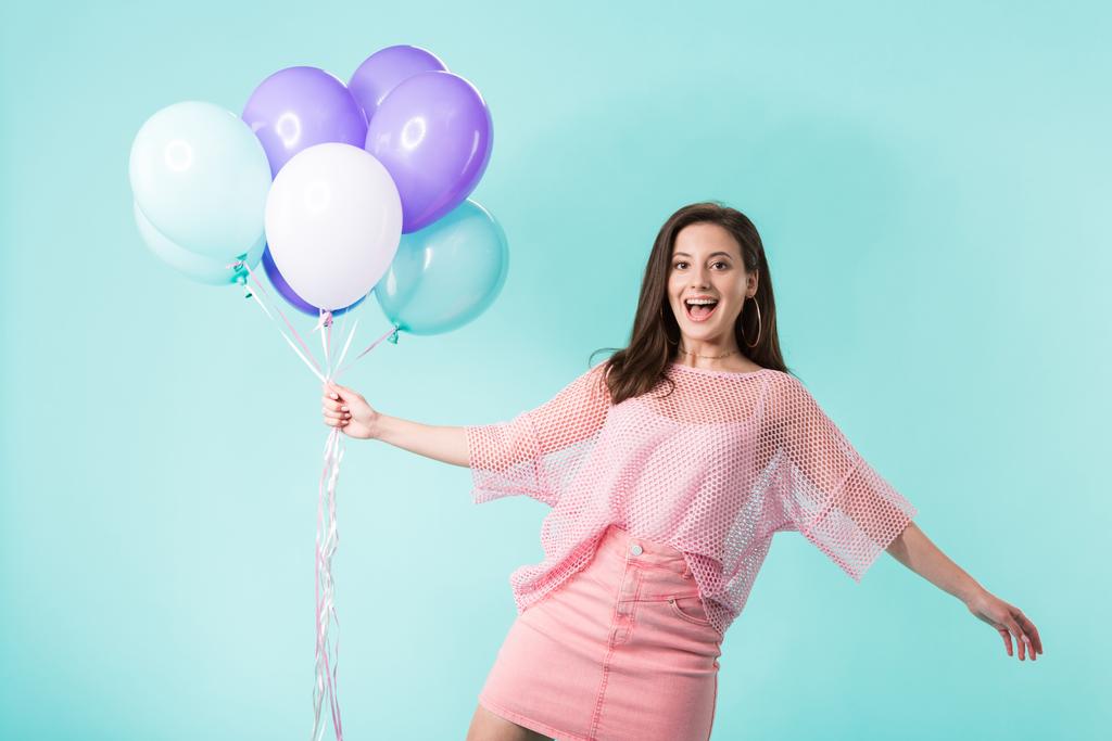 fille heureuse en tenue rose tenant des ballons isolés sur turquoise
 - Photo, image