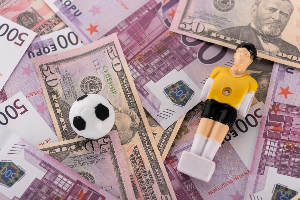 іграшковий футбольний м'яч і футболіст на банкнотах євро і долара, концепція спортивних ставок
 - Фото, зображення